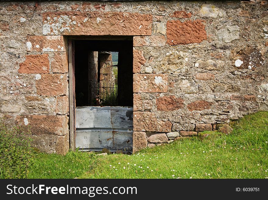 Doorway of a ruined farmhouse against grass. Doorway of a ruined farmhouse against grass