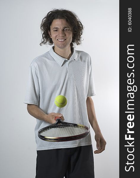 Man smiling as he balances a tennis ball on his racket. Vertically framed photograph. Man smiling as he balances a tennis ball on his racket. Vertically framed photograph.