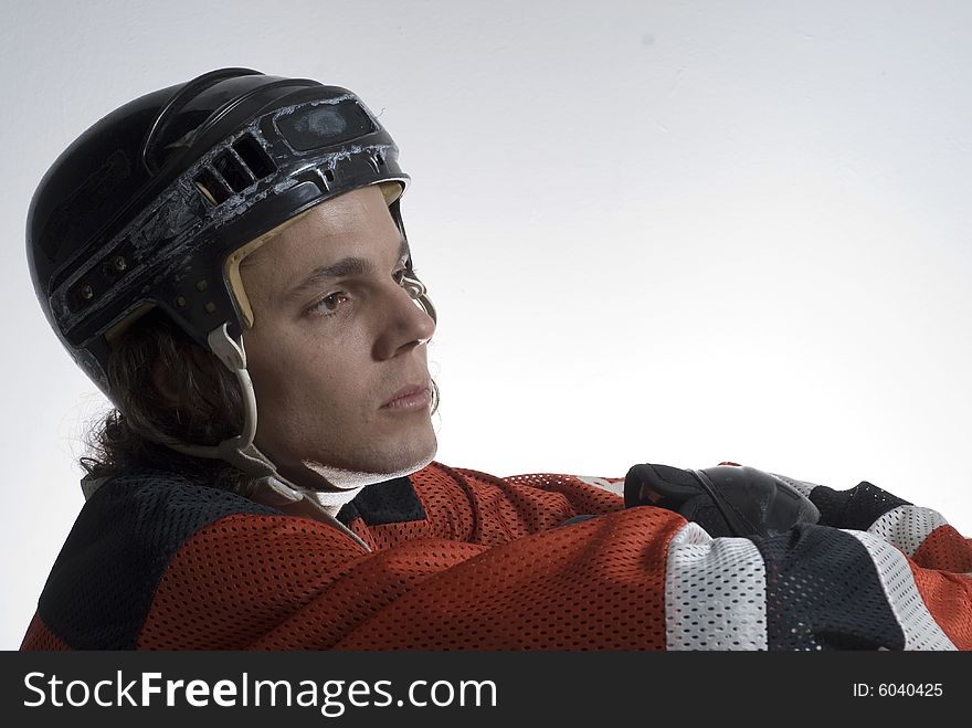 Seated hockey player looks off in the distance with a calm look on his face.  Horizontally framed photograph. Seated hockey player looks off in the distance with a calm look on his face.  Horizontally framed photograph