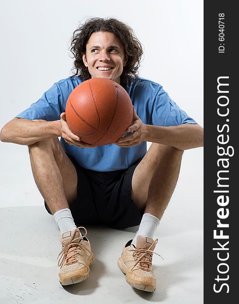 Seated man holds a basketball and smiles.  Vertically framed photograph. Seated man holds a basketball and smiles.  Vertically framed photograph