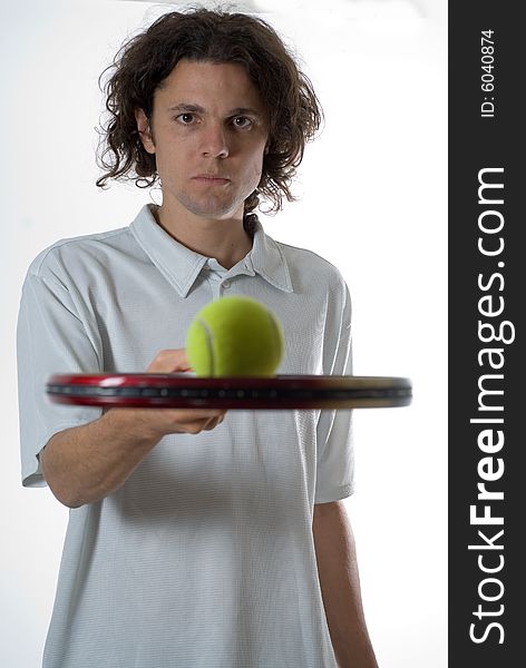 Man holding a tennis racket with a tennis ball and looking at the camera.  Vertically framed photo. Man holding a tennis racket with a tennis ball and looking at the camera.  Vertically framed photo.