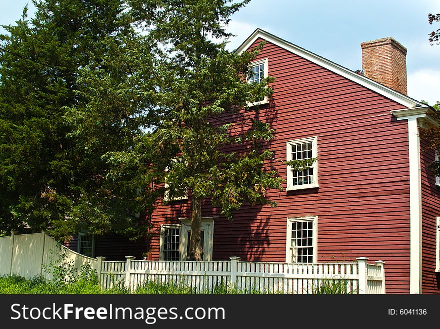 Scenic shot of early american colonial house from the 1700's surrounded by trees. Scenic shot of early american colonial house from the 1700's surrounded by trees