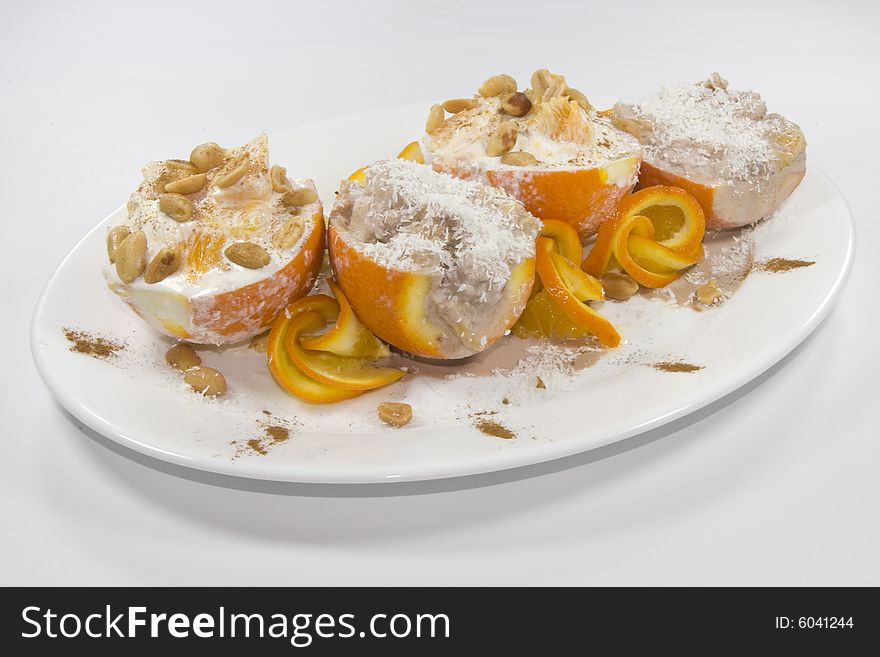 Dish on which oranges with a stuffing from ice-cream from above peanut and coconut shaving are located is. Dish on which oranges with a stuffing from ice-cream from above peanut and coconut shaving are located is