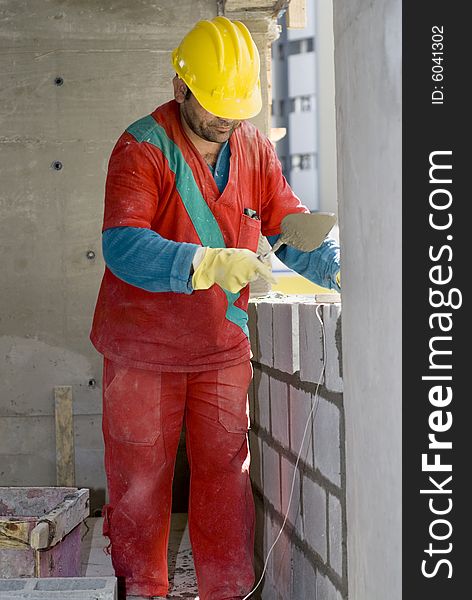 Construction worker builds cinder block wall. Vertically framed photo. Construction worker builds cinder block wall. Vertically framed photo.