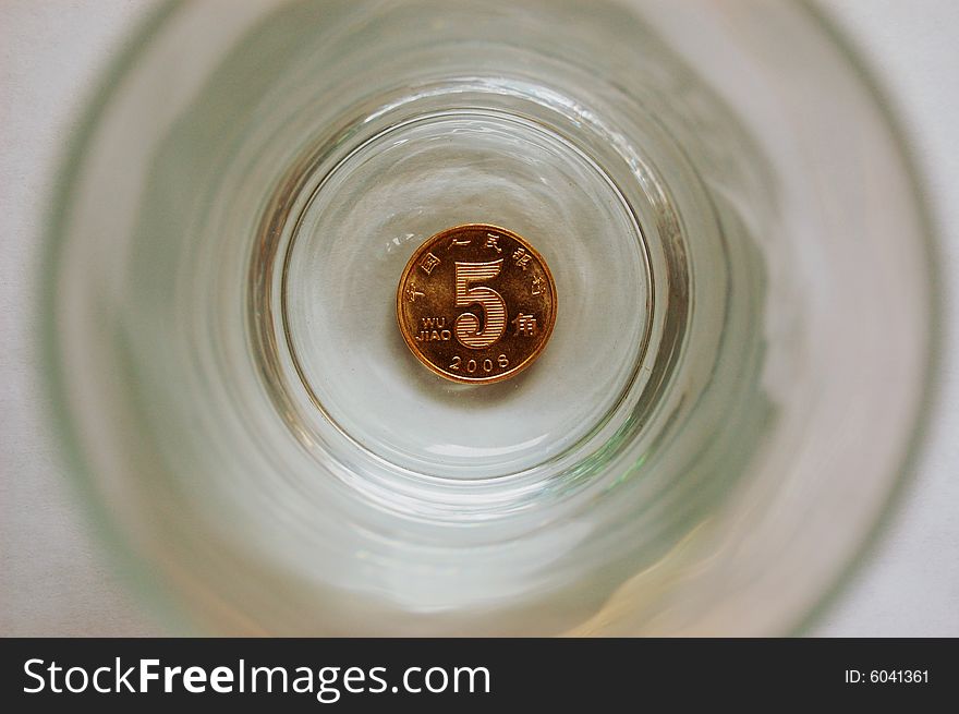 Coin in center bottom of a glass cup,view from top of glass cup. Coin in center bottom of a glass cup,view from top of glass cup