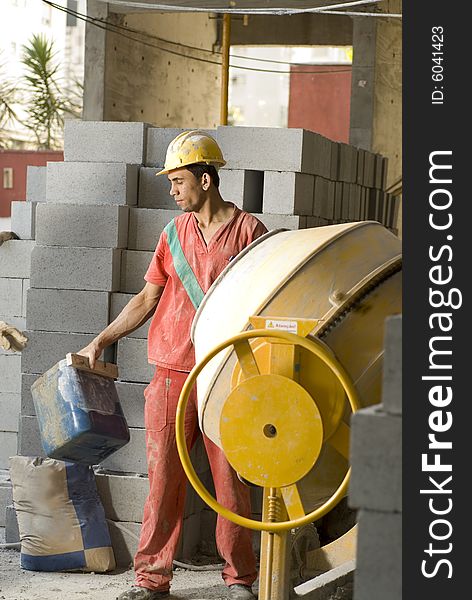 Construction worker stands in front of cement mixer. Vertically framed photo. Construction worker stands in front of cement mixer. Vertically framed photo.