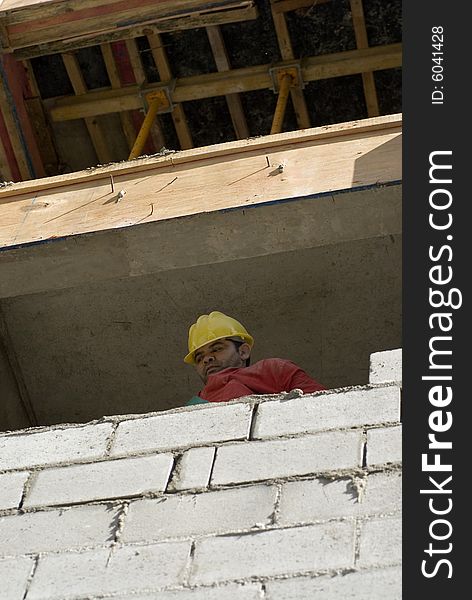 Construction worker looks over newly constructed cinder block wall. Vertically framed photo. Construction worker looks over newly constructed cinder block wall. Vertically framed photo.