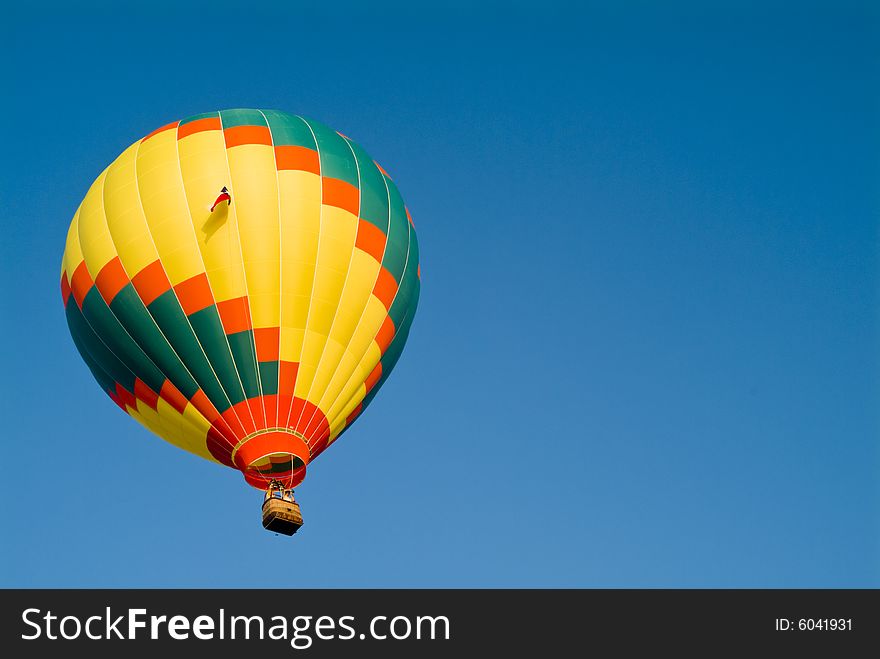 A colorful hot air balloon floating in a bright blue sky. A colorful hot air balloon floating in a bright blue sky.