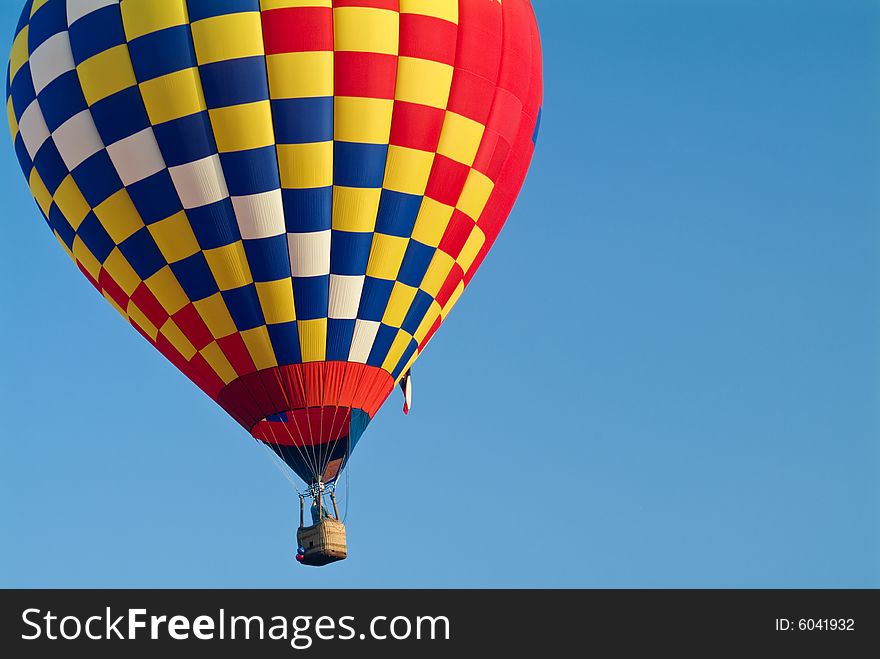 A colorful hot air balloon floating in a bright blue sky. A colorful hot air balloon floating in a bright blue sky.