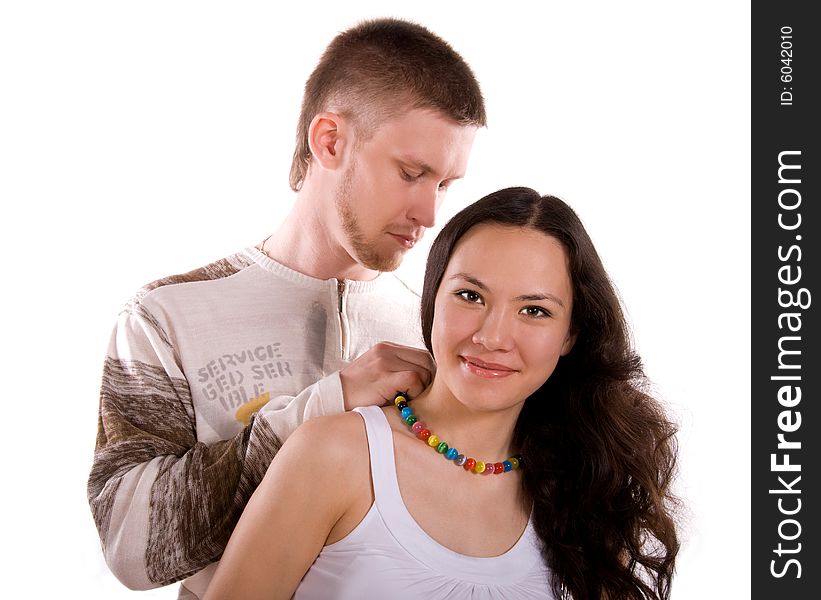 Loving young man puts a beads on the girl against white background. Loving young man puts a beads on the girl against white background