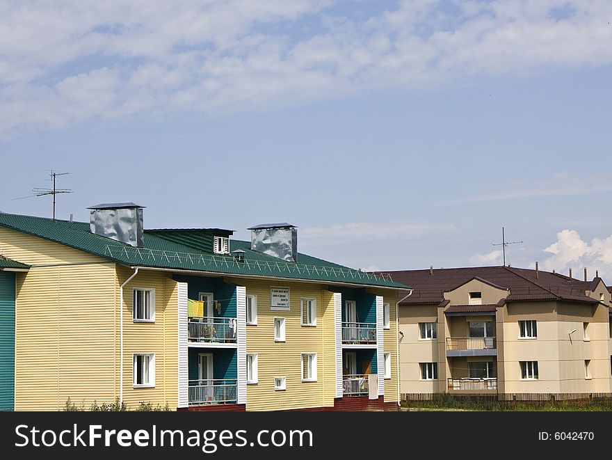 Two houses two floors, brown and green roofs, yellow walls. Two houses two floors, brown and green roofs, yellow walls