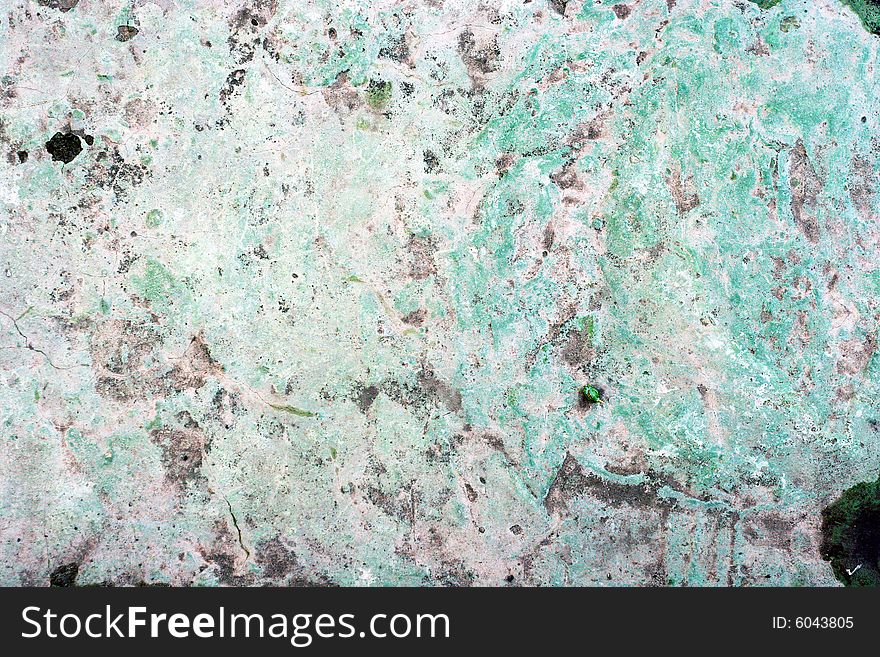 Concrete wall with cracked gray paint worn by weather.