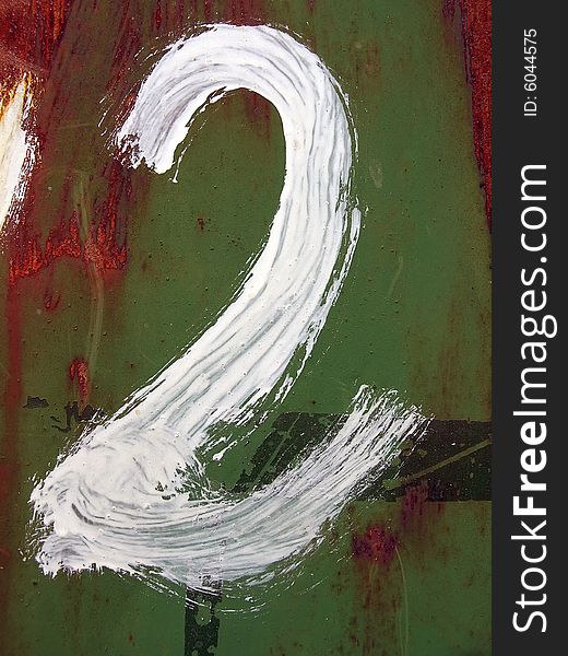 The figure two is drawn by a white paint on a rusty metal background.