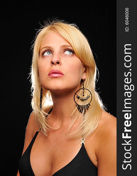 Gorgeous young blond woman wearing earings against a black background