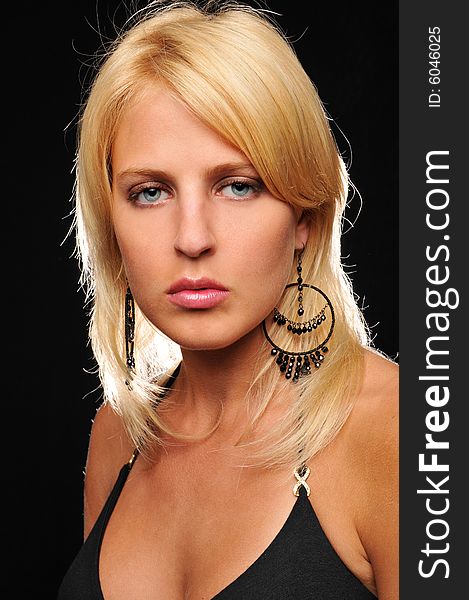 Gorgeous young blond woman wearing earings against a black background