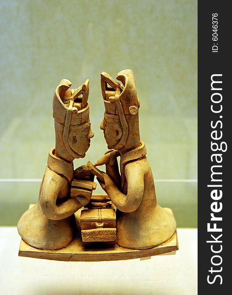 Pottery figures of two men studying together face to face