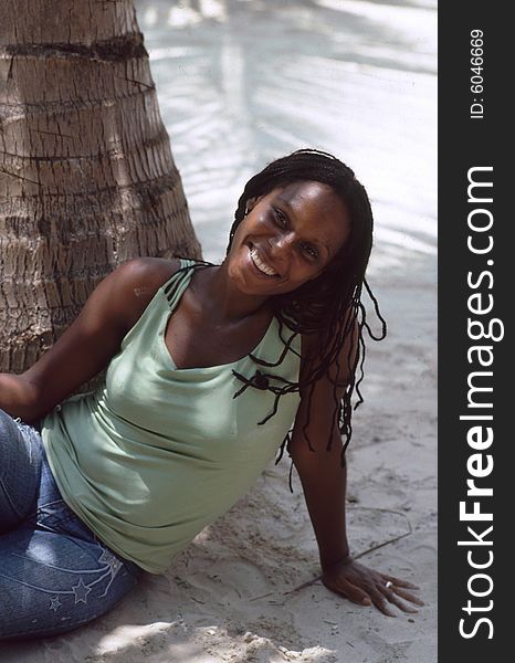 Caribeean girl on the beach sitting under palmtree. Caribeean girl on the beach sitting under palmtree
