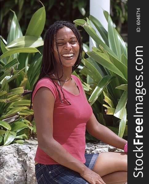 Caribbean lady on the beach sitting beyond green bushes and laughing. Caribbean lady on the beach sitting beyond green bushes and laughing