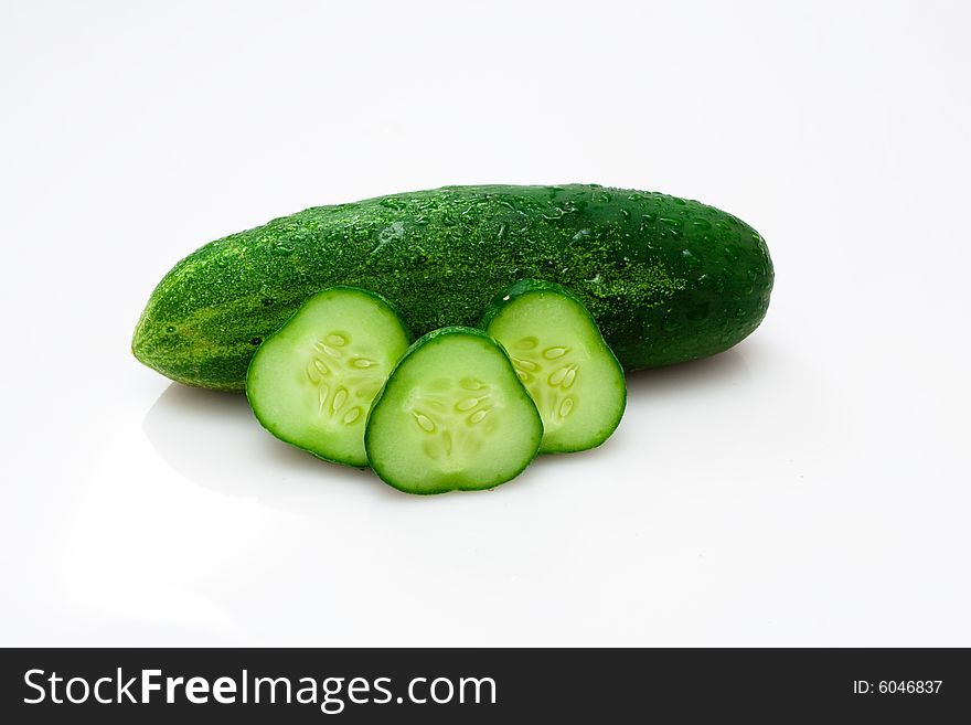 Fresh cucumbers slices on white with water drops.