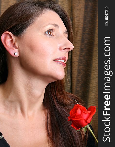 Brunette model holding a red rose, looking into the distance. Brunette model holding a red rose, looking into the distance