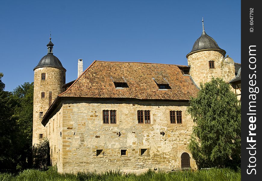 German castle with two towers and made from natural stone at the summertime