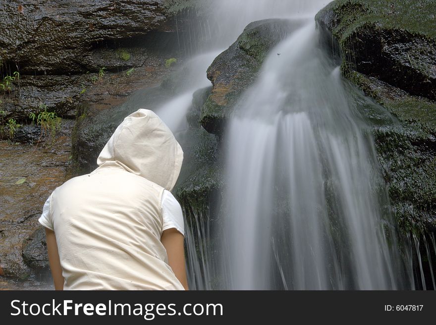 Girl is sitting in front of waterfall. Girl is sitting in front of waterfall