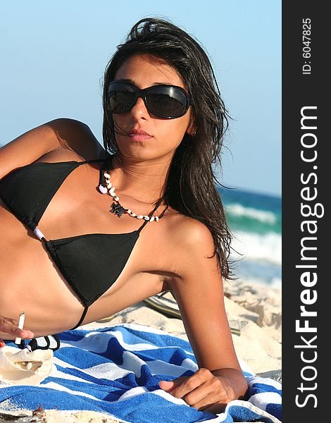 Young woman in big sunglasses and bikini laying on sea beach / Good and slim shape. Young woman in big sunglasses and bikini laying on sea beach / Good and slim shape