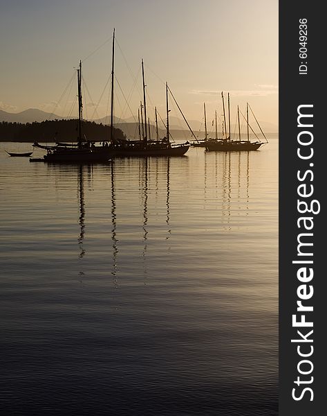 Sailboats anchored in calm waters at dusk. Sailboats anchored in calm waters at dusk.