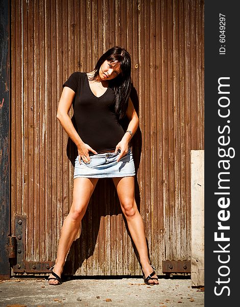 Young lady in miniskirt standing near an old wooden door. Young lady in miniskirt standing near an old wooden door