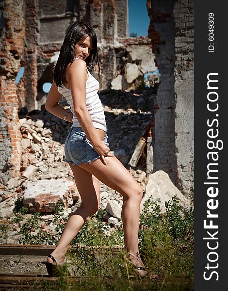 Young tanned girl in the environment of ruins of an old factory. Young tanned girl in the environment of ruins of an old factory