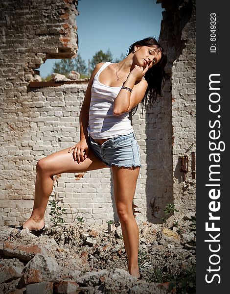 Attractive woman in jeans shorts sucking her finger standing on ruins. Attractive woman in jeans shorts sucking her finger standing on ruins
