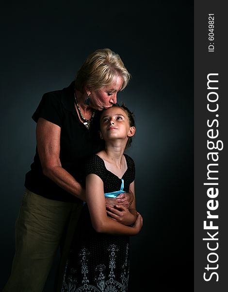 Grandmother kissing granddaughter on forehead