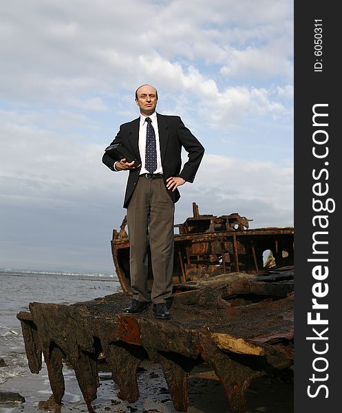 A businessman standing middle of a rusting ship looking out for a bright business future. A businessman standing middle of a rusting ship looking out for a bright business future.