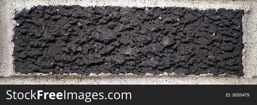 Single black brick surrounded by cement