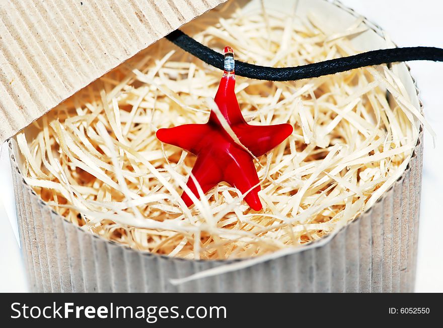 Red starfish glass necklace in pasteboard box close up. Red starfish glass necklace in pasteboard box close up