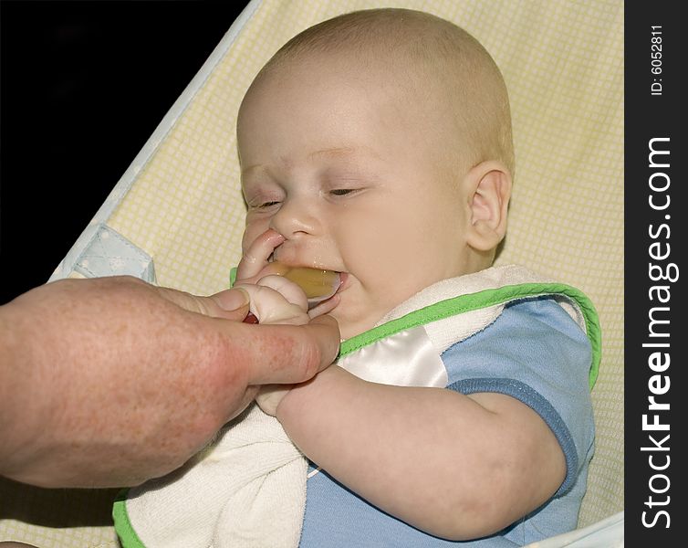 A six month old baby boy enjoying his lunch. A six month old baby boy enjoying his lunch