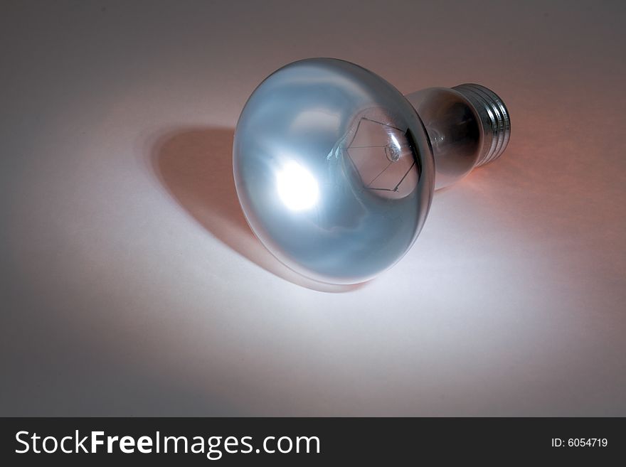 Glassy electric lamp lying on colored background. Glassy electric lamp lying on colored background