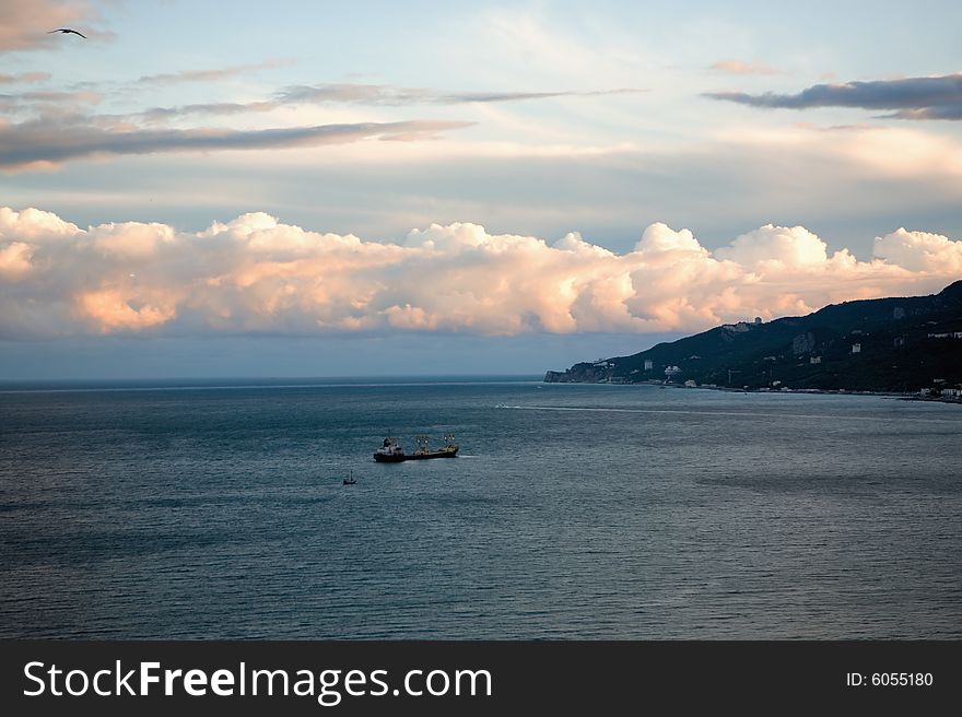 Seascape with dry cargo ship at sunset