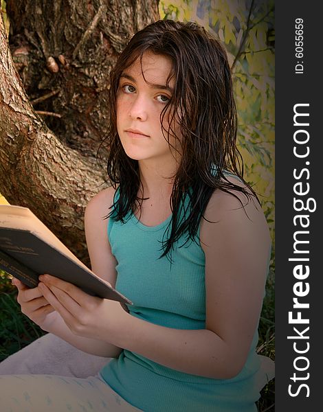 Teen girl reading a book under a tree. Teen girl reading a book under a tree