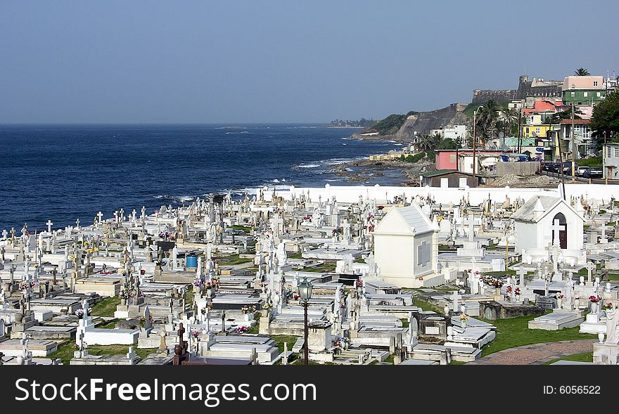 The view of a cemetery by the sea with La Perla district and historic fort in a background in the old city of San Juan, the capital of Puerto Rico. The view of a cemetery by the sea with La Perla district and historic fort in a background in the old city of San Juan, the capital of Puerto Rico.