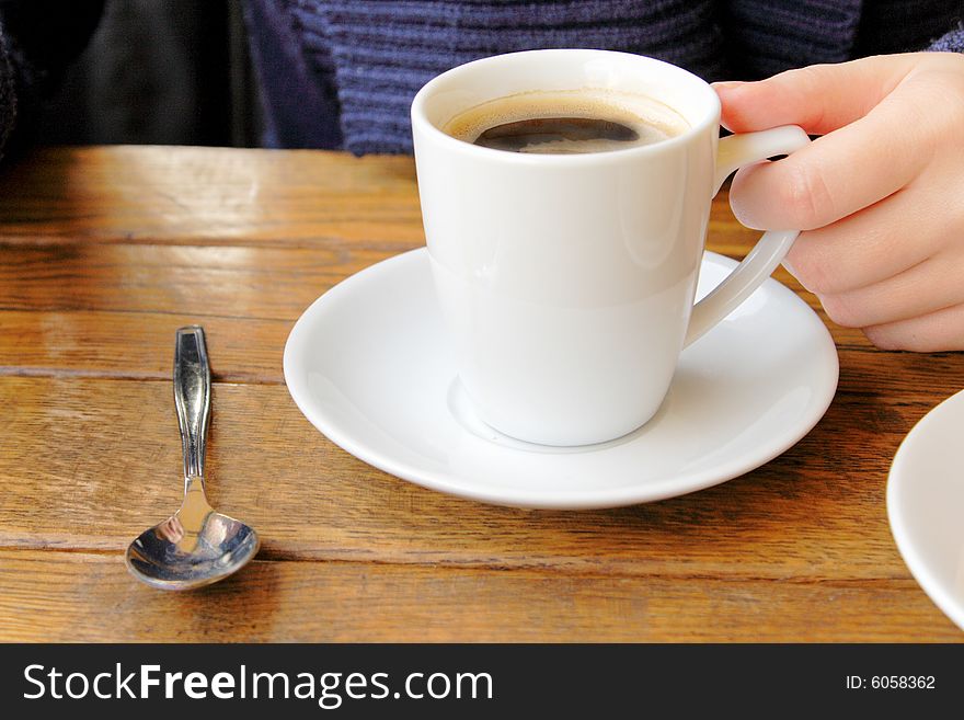 Female hand holding a cup of coffee in cafe