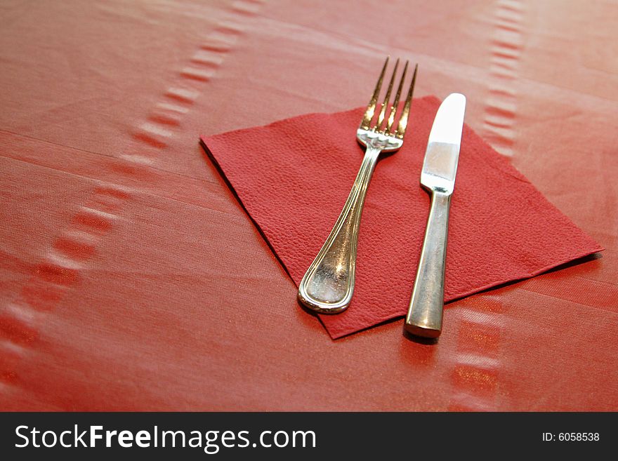 Fork and knife with red napkin on the table. Fork and knife with red napkin on the table