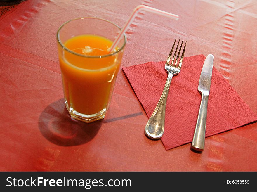 Dinnerware and glass of juice on red tablecloth in the restaurant. Dinnerware and glass of juice on red tablecloth in the restaurant