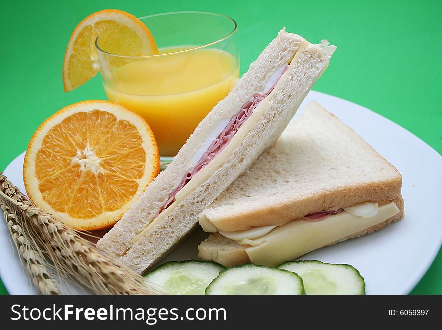 A glas of orange juice and sandwiches. A glas of orange juice and sandwiches