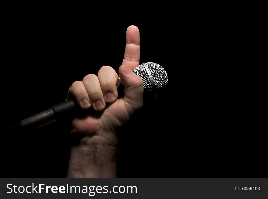 Microphone clinched firmly in male fist with index finger pointing up. Microphone clinched firmly in male fist with index finger pointing up.