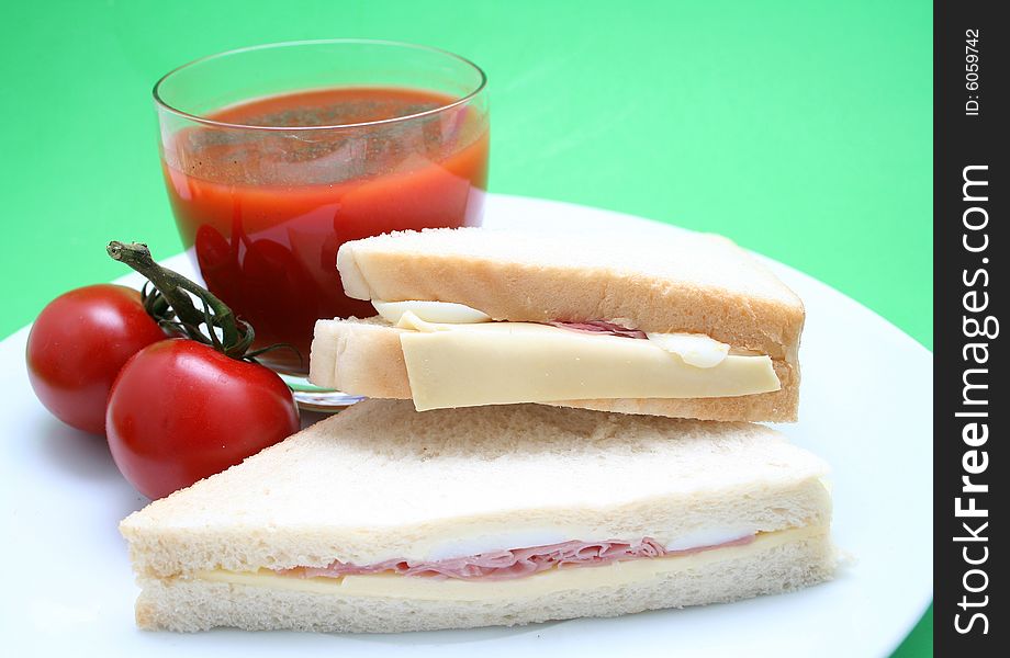 Two sandwiches with cheese and baccon and a tomatojuice. Two sandwiches with cheese and baccon and a tomatojuice