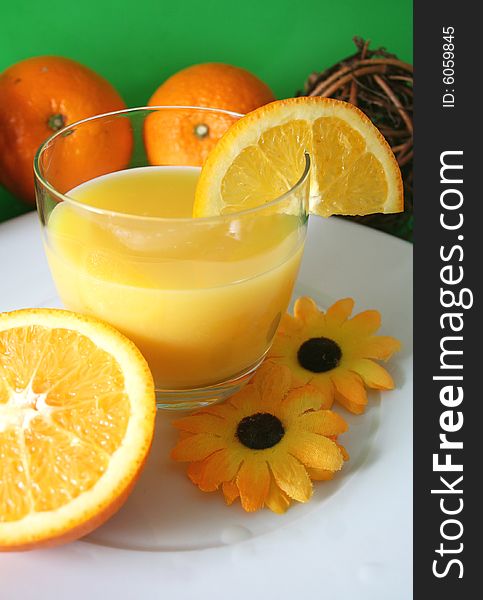 A fresh made orange juice and some oranges