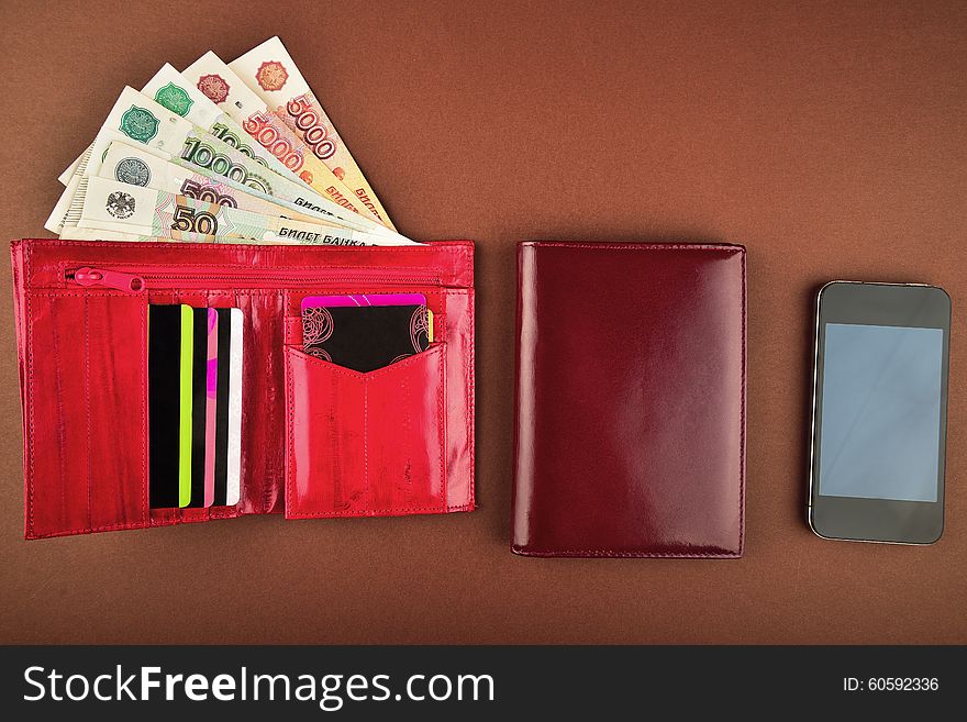 Purse,money, wallet and phone on a brown background