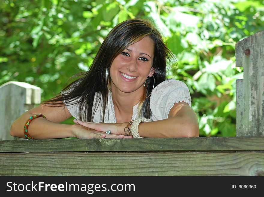 A young lady leans on the wooden rail of a bridge. A young lady leans on the wooden rail of a bridge