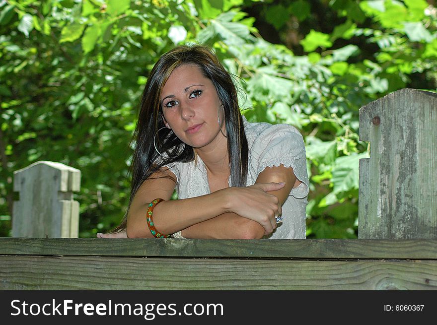 A young lady leans on the wooden rail of a bridge. A young lady leans on the wooden rail of a bridge